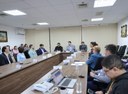 Pessoas participam de reunião em sala com mesa ampla
